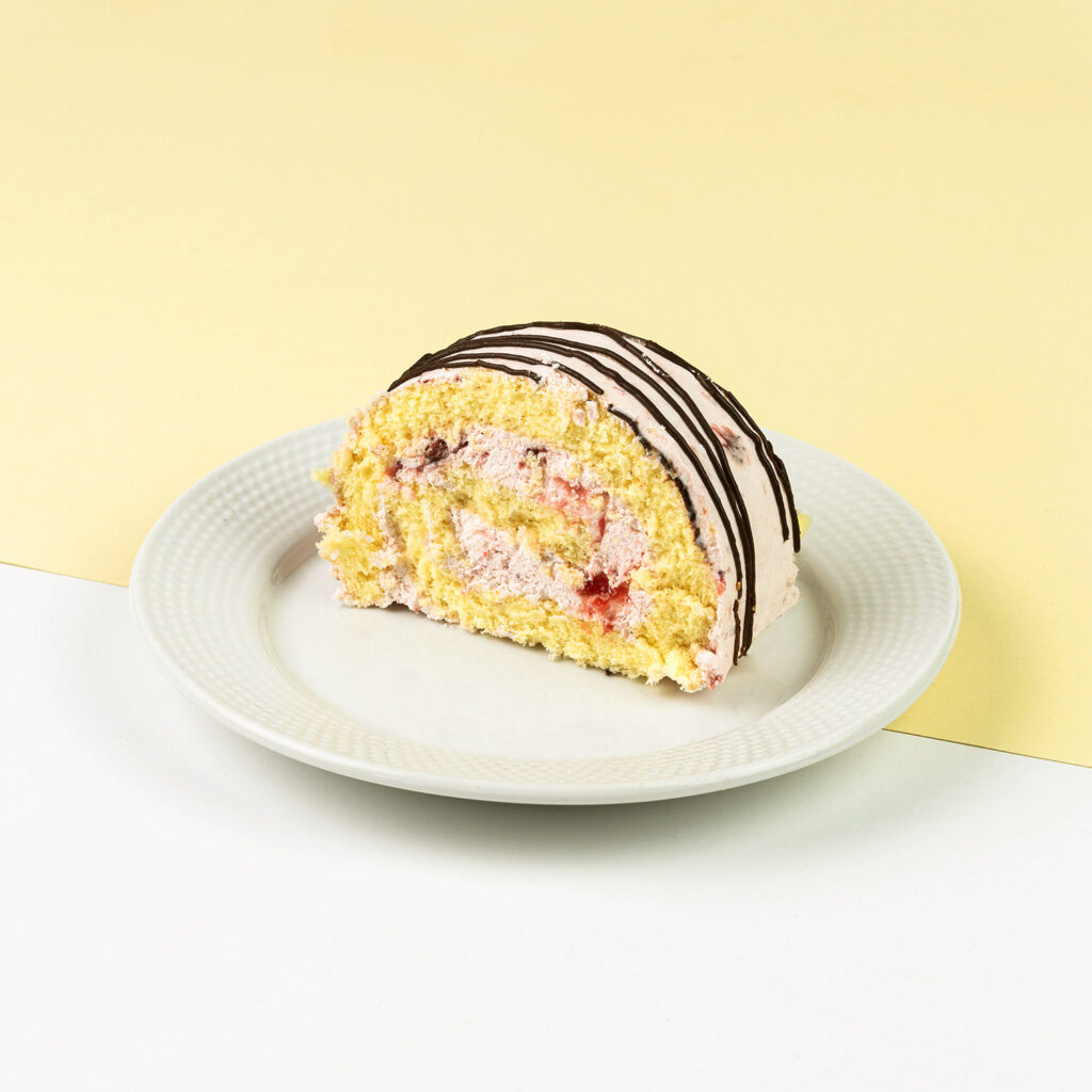 Ciasto biszkoptowe przełożone bitą śmietaną z musem truskawkowym, udekorowane czekoladą