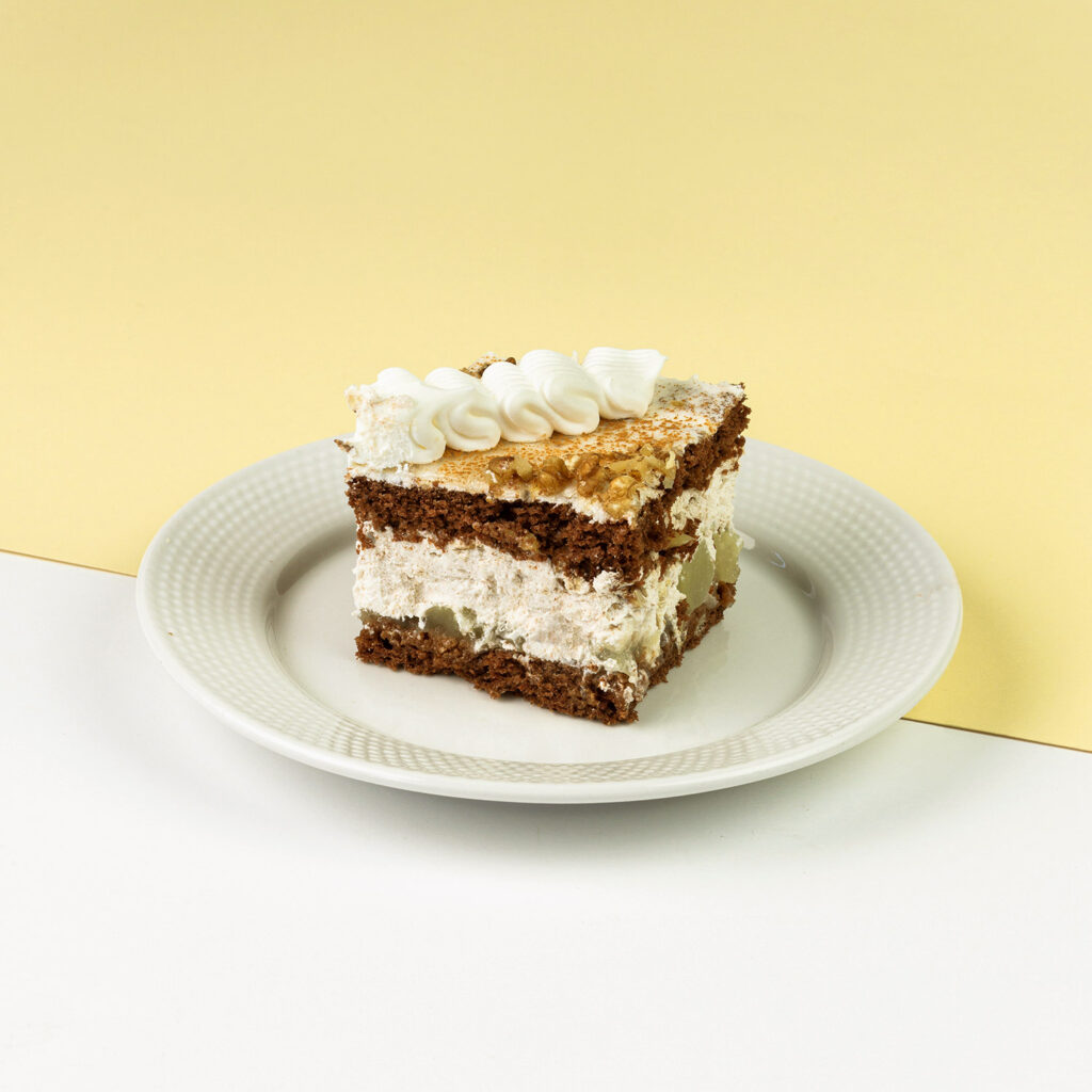 Czekoladowe biszkopty przełożone śmietaną z jabłkami, całość dekorowana orzechem włoskim oraz cynamonem