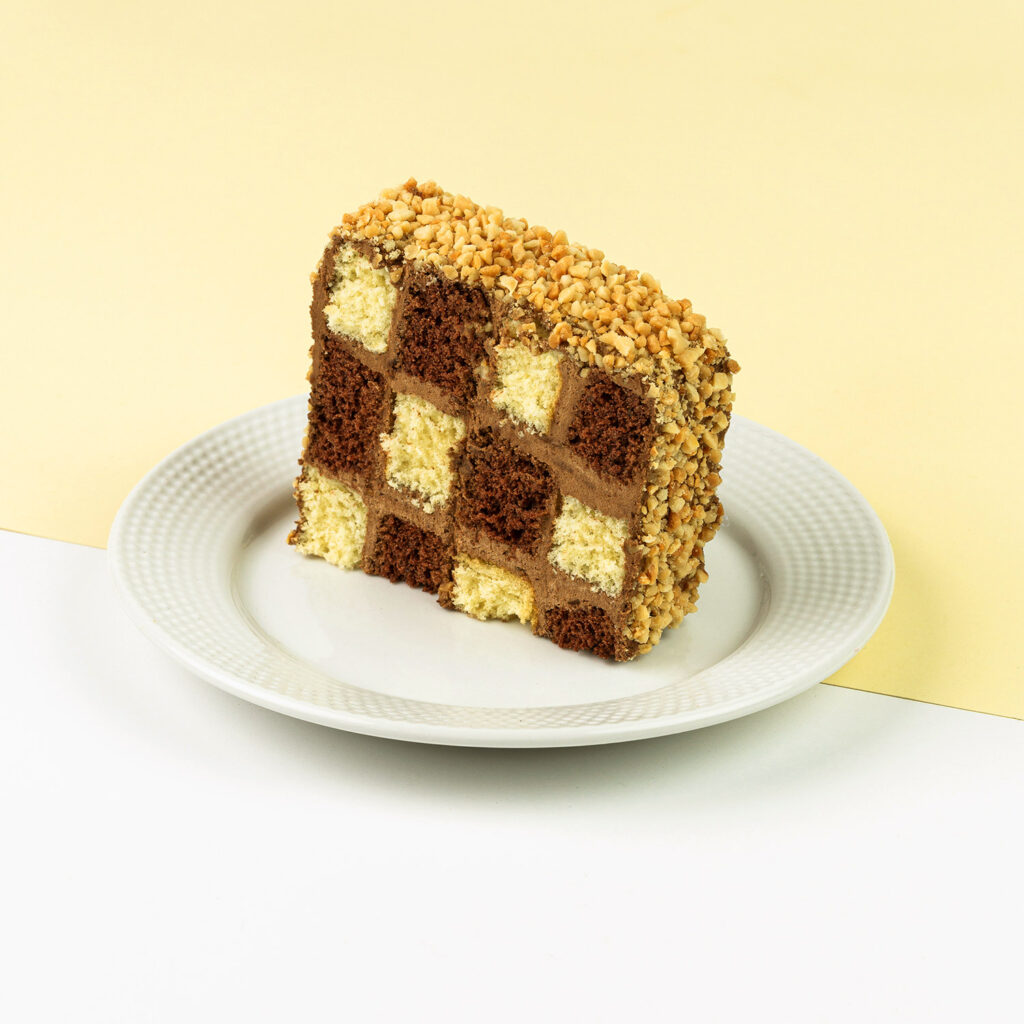 Biszkopt śmietankowo-czekoladowy przełożony kremem, wykończony orzechami arachidowymi