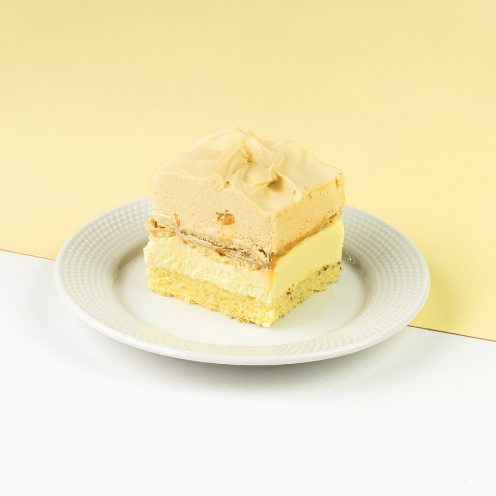 Biszkopt przełożony kremem toffi oraz krakersami, wykończony bitą śmietaną o smaku toffi