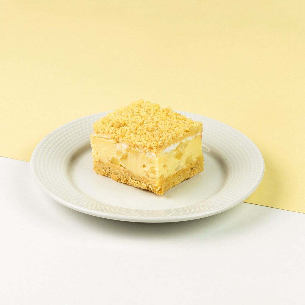 Kruchy spód, delikatny krem budyniowy z jabłkami, całość udekorowana lekką kruszonką