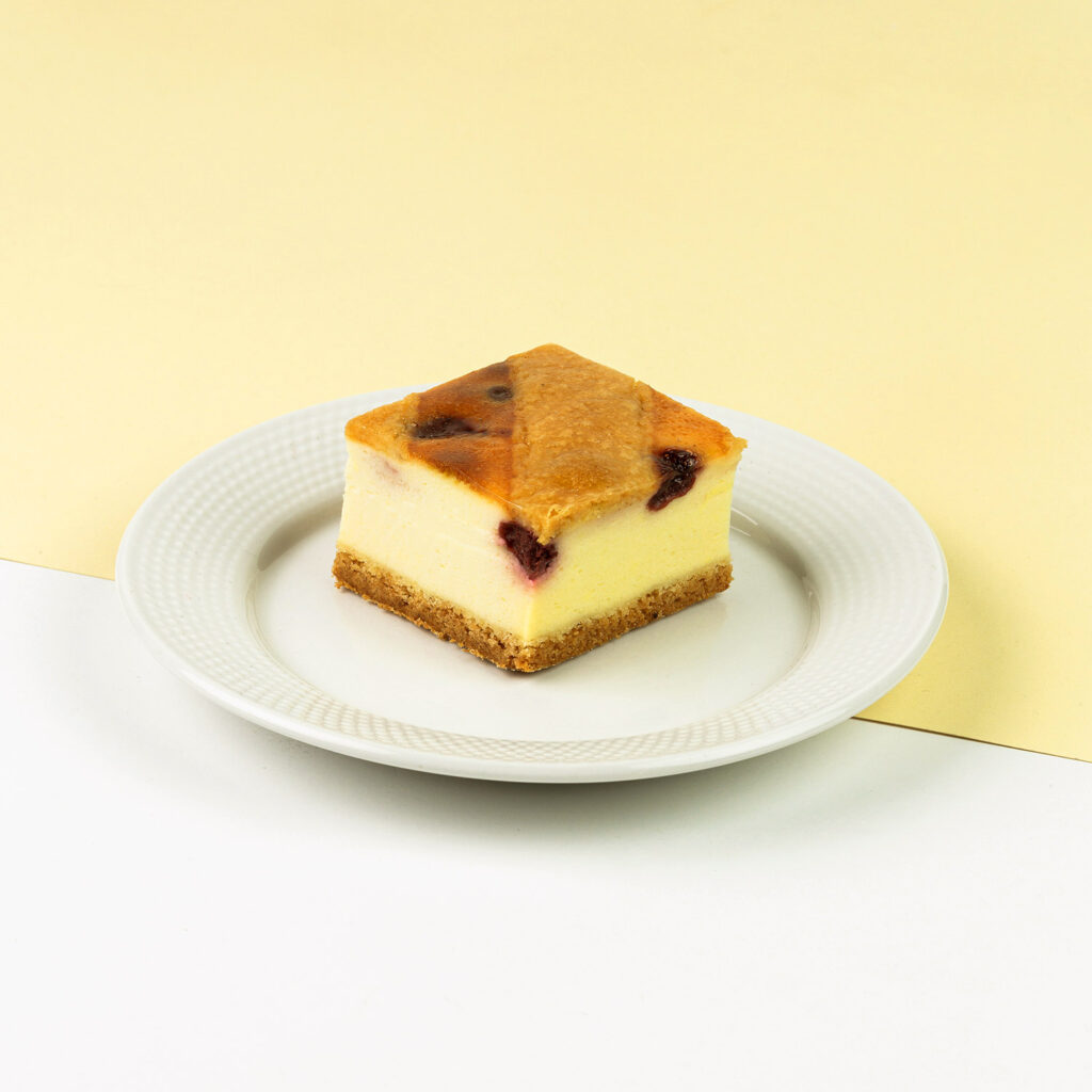 Kruchy spód, delikatna masa serowa z dodatkiem wiśni, całość pokryta żelem morelowym