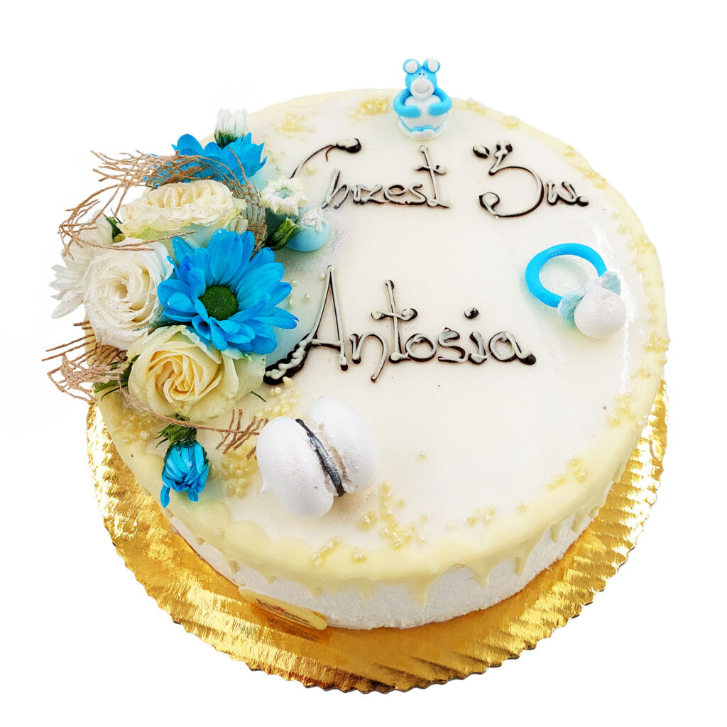 Tort z napisem czekoladowym Chrzest Św. Antosia ozdobiony białymi oraz jasnoniebieskimi kwiatami. Małe zdobienia jasnoniebieski smoczek, miś, oraz białe ciasteczko z nadzieniem.