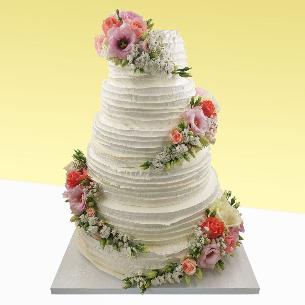 Torty weselne. Tort weselny z białą masą ozdobiony różami herbacianymi i białymi, oraz kwiatkami. Torty na zamówienie.