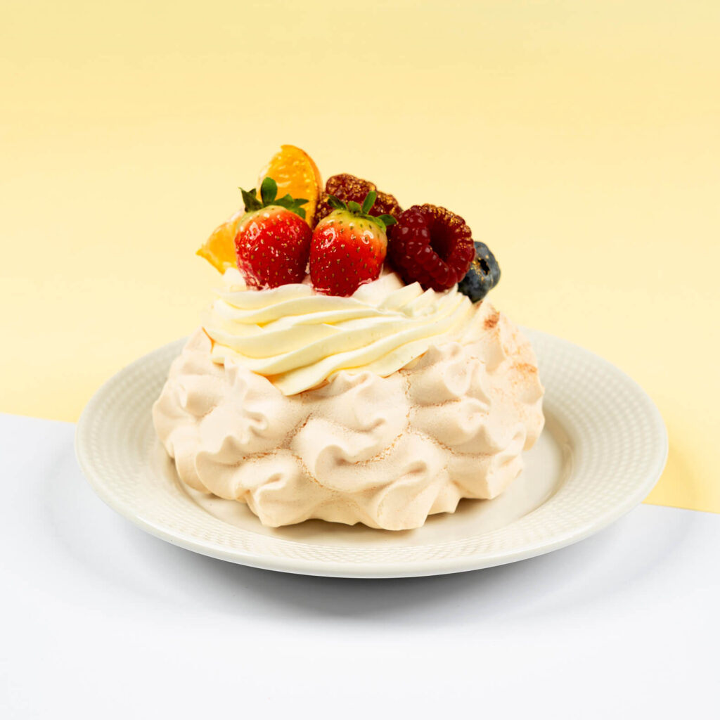 Mini beza z frużeliną z czarnej porzeczki, bita śmietana z mascarpone, całość bogato dekorowana owocami