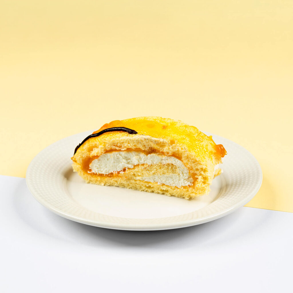 Ciasto biszkoptowe przełożone bitą śmietaną z frużeliną brzoskwiniową, udekorowane czekoladą