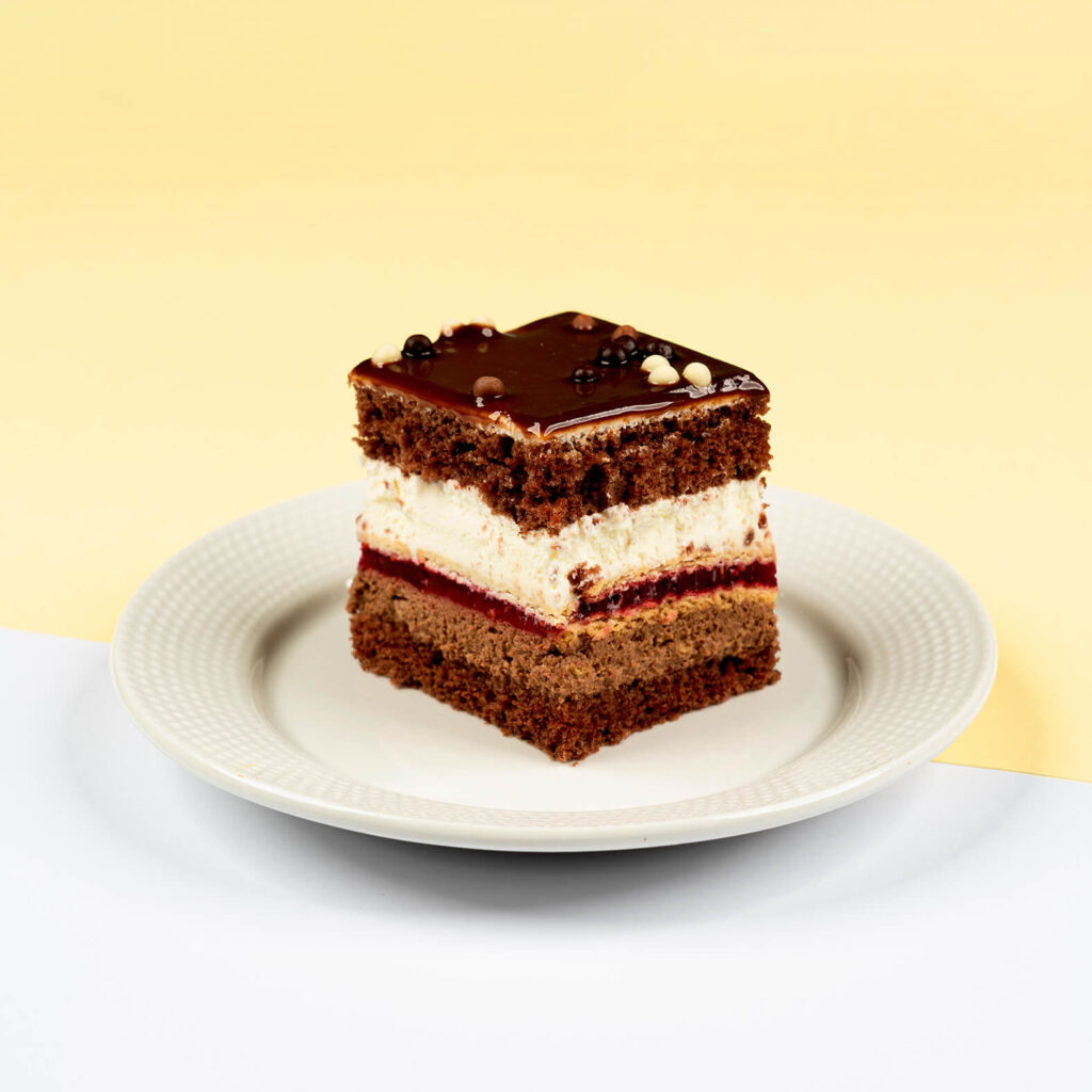 Połączenie czekoladowych biszkoptów, kremu czekoladowego z orzechami arachidowymi, herbatników przełożonych żelką malinową oraz puszystego kremu śmietankowego, całość wykończona czekoladą z prażynką